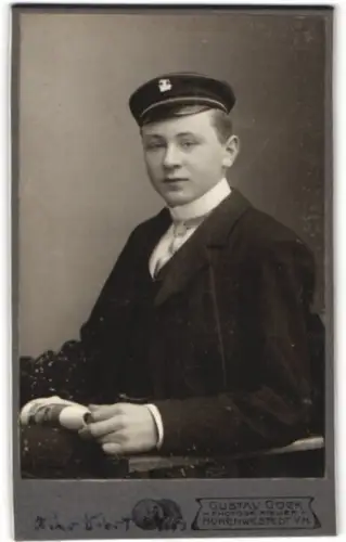 Fotografie Gustav Goek, Hohenwestedt, Portrait eines jungen Student im dunklen Anzug mit Mütze