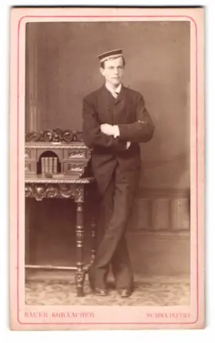 Fotografie Bauer-Kornacher, Schweinfurt, Hellersgasse 9, eleganter junger Student im Anzug lehnt an einem Sekretär