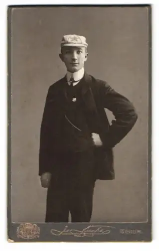 Fotografie J. Fuchs, Berlin, C. KönigStr. 52, Stehender junger Mann im Anzug mit Esperanto Mütze