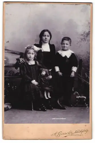 Fotografie A. Gieseler Nachfolg., Ingolstadt, Milchstr. 14, Drei Kinder mit grosser Puppe und Zöpfen