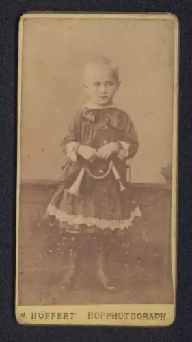 Fotografie W. Höffert, Ort unbekannt, Porträt eines jungen Kindes mit Spielzeug Horn