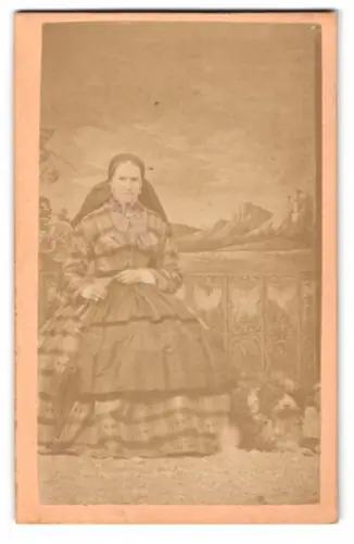 Fotografie J. Merzederk, Kremsmünster, Frau in Tracht mit Hund vor einer Studiokulisse