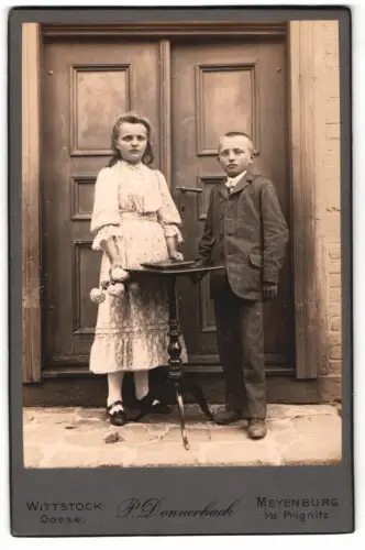 Fotografie P. Donnerhack, Wittstock Dosse, Zwei Kinder in eleganter Kleidung vor Doppeltür