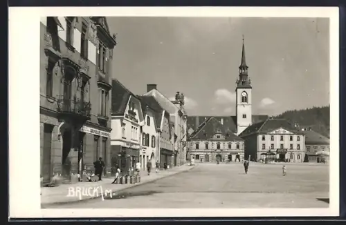 AK Bruck a. d. Mur, Platzpartie mit Geschäften und Kirchturm