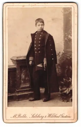 Fotografie Max Balde, Salzburg, junger Knabe in Uniform als Kadett mit Mantel