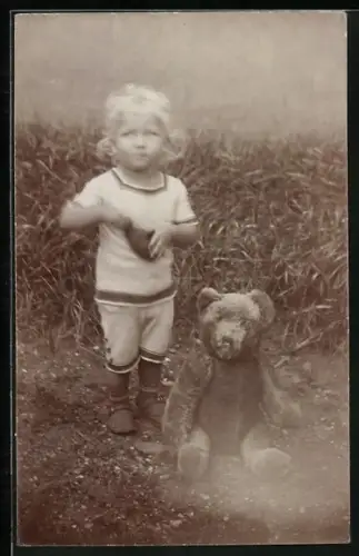 Foto-AK Kleinkind mit einem Teddy im Garten