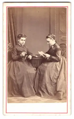 Fotografie Heer-Tschudi, Lausanne, Rue St Francois 20, Zwei Frauen Clara und Anna in dunklen Kleidern am Tisch sitzend