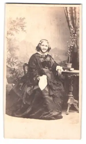 Fotografie unbekannter Fotograf und Ort, Dame in elegantem Kleid neben Tisch
