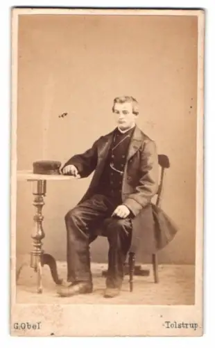 Fotografie G. Obel, Tolstrup, Eleganter Herr an Tisch sitzend