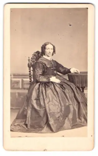 Fotografie Heer-Tschudi, Lausanne, Rue St Francois 20, Dame im prachtvollen Kleid am Tisch sitzend