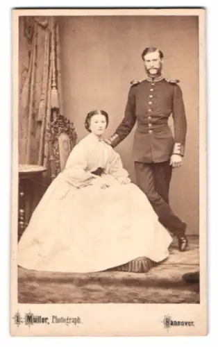 Fotografie L. Müller, Hannover, Elegantes Paar im Atelier, Soldat in Gardeuniform mit Epauletten