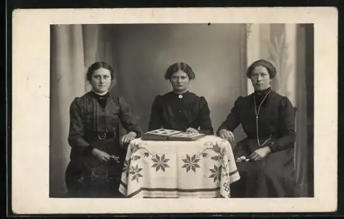 Foto-AK Drei Frauen beim Betrachten von einem Ansichtskarten-Album