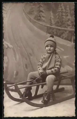 Foto-AK Kind in Winterkleidung auf einem Schlitten