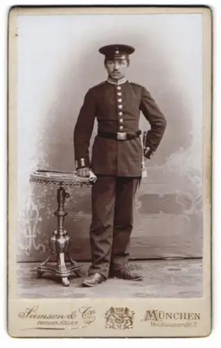Fotografie Samson & Co, München, Neuhauserstr. 7, Soldat in Garde Uniform neben einem Tisch