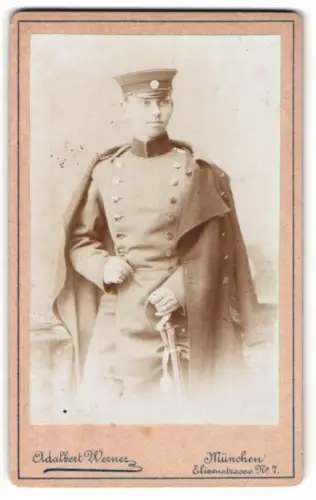 Fotografie Adalbert Werner, München, Elisenstrasse Nr. 7, Porträt eines Soldaten in Uniform mit Mantel und Säbel, 1893