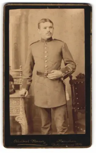 Fotografie Adalbert Werner, München, Dachauerstrasse 6, Soldat im Uniformporträt nebst Raupenhelm auf dem Tisch