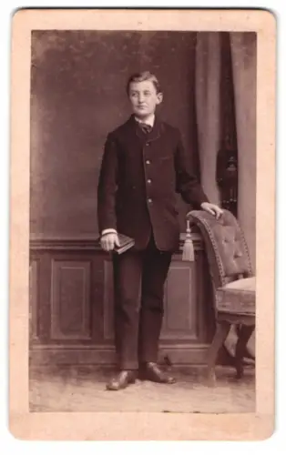 Fotografie unbekannter Fotograf und Ort, Junger Mann mit Buch und Stuhl