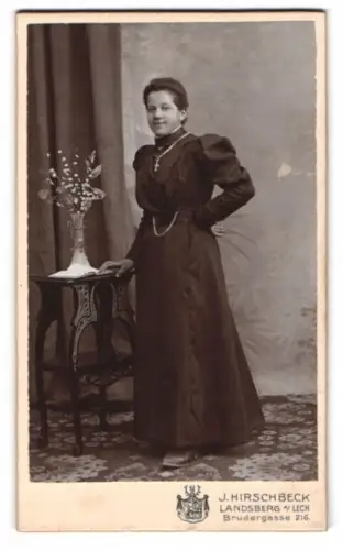 Fotografie J. Hirschbeck, Landsberg am Lech, Brudergasse 216, Frau neben einem Tisch mit Blumenvase