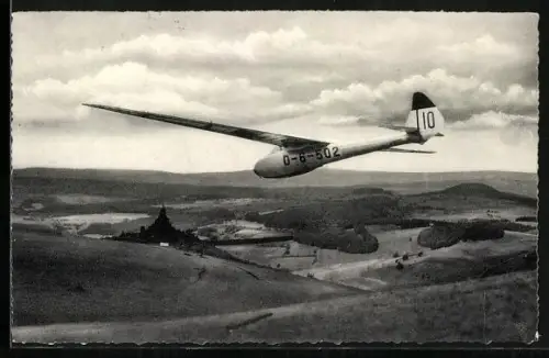 AK Segelflugzeug über der Wasserkuppe mit Blick zum Fliegerdenkmal