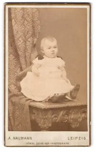 Fotografie Alfred Naumann, Leipzig, Dorotheenstrasse, Sitzendes Kleinkind auf dekorativem Tisch