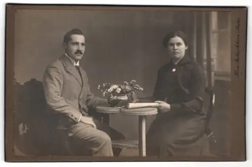 Fotografie Max Pache, Achern i. Baden, Paar am Tisch mit Blumen