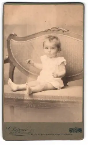 Fotografie C. Pietzner, Brünn, Kleinkind auf Sofa sitzend