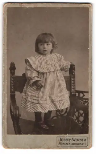 Fotografie Joseph Werner, München, Isartorplatz 2, Kleines Kind in gestreiftem Kleid auf Stuhl