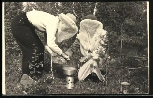 Fotografie zwei Frauen mit Moskito Schutz bereiten Choucroute garnie Gericht zu, Gaskocher