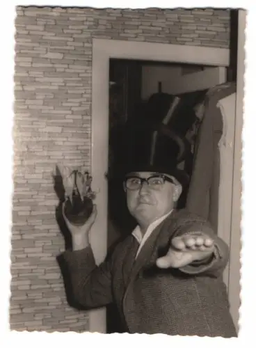 Fotografie Mann mit doppel Zylinder auf dem Kopf wirft mit Krokus nach der Kamera