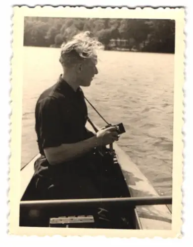 Fotografie junger blonder Hobbyfotograf knipst Bilder aus einem Ruderboot heraus