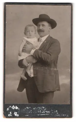 Fotografie Jos. Werkmeister, Traunstein, Ludwigstrasse 14, Porträt eines Mannes mit Kind im Arm