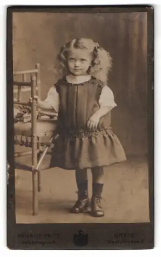 Fotografie Heinrich Fritz, Greiz, Weststrasse 6, Mädchen im Kleid neben Stuhl