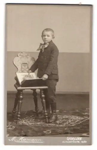 Fotografie M. Hamann, Görlitz, Elisabethstr. 10/11, Junge mit Buch vor dekorativem Stuhl