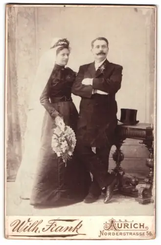 Fotografie Wilh. Frank, Aurich, Norderstrasse 56, Hochzeitspaar im Atelier mit schwarzen Brautkleid
