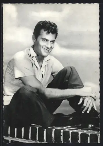 AK Portrait des Schauspielers Tony Curtis auf Mauer sitzend