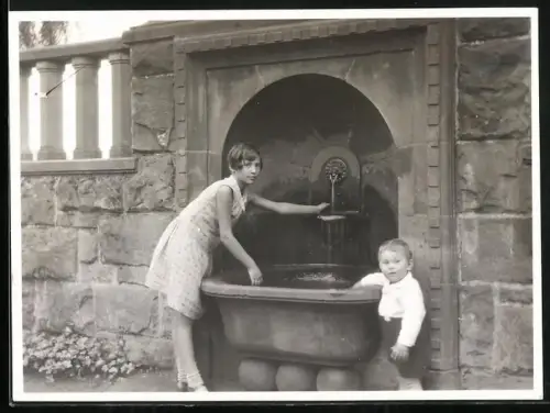 Fotografie junge Frau und kleiner Junge an einem Brunnen