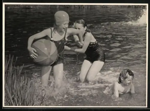 Fotografie Kinder beim Baden in Badeanzügen mit Schwimmkappe und Wasserball