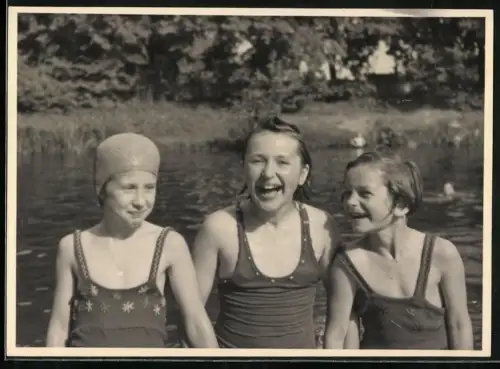 Fotografie drei Mädchen in Badeanzügen kommen nass aus dem Wasser