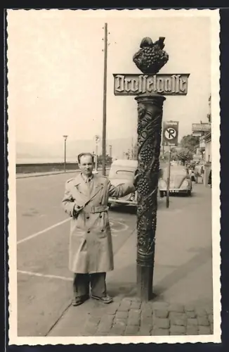 Foto-AK Rüdesheim / Rhein, Drosselgasse - Impression 50er Jahre, Herr in Mantel an Schild gelehnt