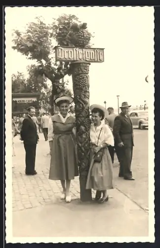 Foto-AK Rüdesheim / Rhein, Drosselgasse - Impression 50er Jahre, Zwei Damen in Kleidern am Schild