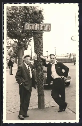 Foto-AK Rüdesheim / Rhein, Drosselgasse - Impression 50er Jahre, Zwei junge Herren in Anzügen am Schild angelehnt