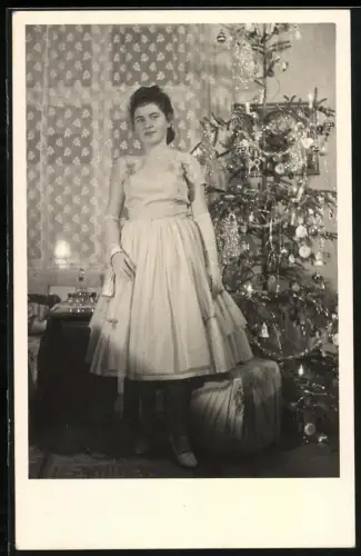 Fotografie junge Frau zu Weihnachten vor dem geschmückten Weihnachtsbaum, 1960