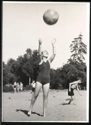 Fotografie junge Frau im Badeanzug spielt mit Strandball im Sand