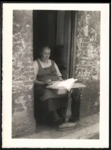 Fotografie ältere Dame im Hauseingang beim Klöppeln, Hausarbeit