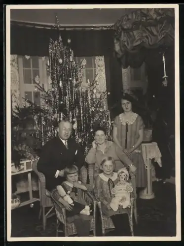 Fotografie Familie mit Kindern zu Weihnachten mit Puppen als Geschenkt, Weihnachtsbaum mit Lametta