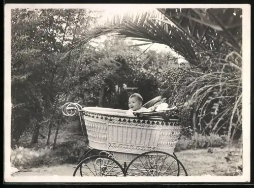 Fotografie niedliches kleines Kind schaut aus seinem Kinderwagen