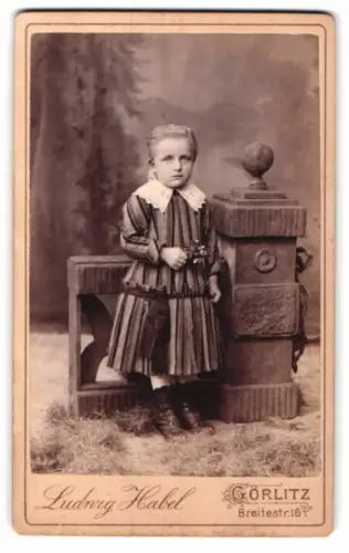 Fotografie Ludwig Habel, Görlitz, Breitestr. 16, Kind in gestreiftem Kleid mit Blumenstrauss