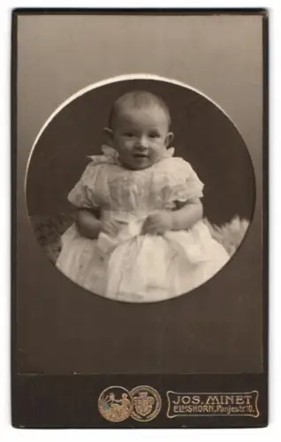 Fotografie Jos. Minet, Elmshorn, Panjestr. 10, Porträt eines Kleinkindes in weissem Kleid