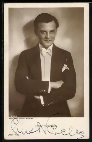 AK Schauspieler Ernst Verebes im Anzug mit verschränkten Armen an einer Wand stehend, Autograph