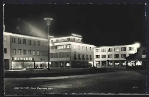 AK Knittelfeld /Stmk., Kapuzinerplatz mit Geschäften bei Nacht
